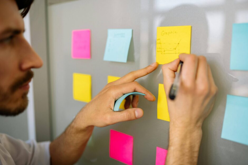 Photo designer UX en train de noter sur des post-its accrochés sur un mur